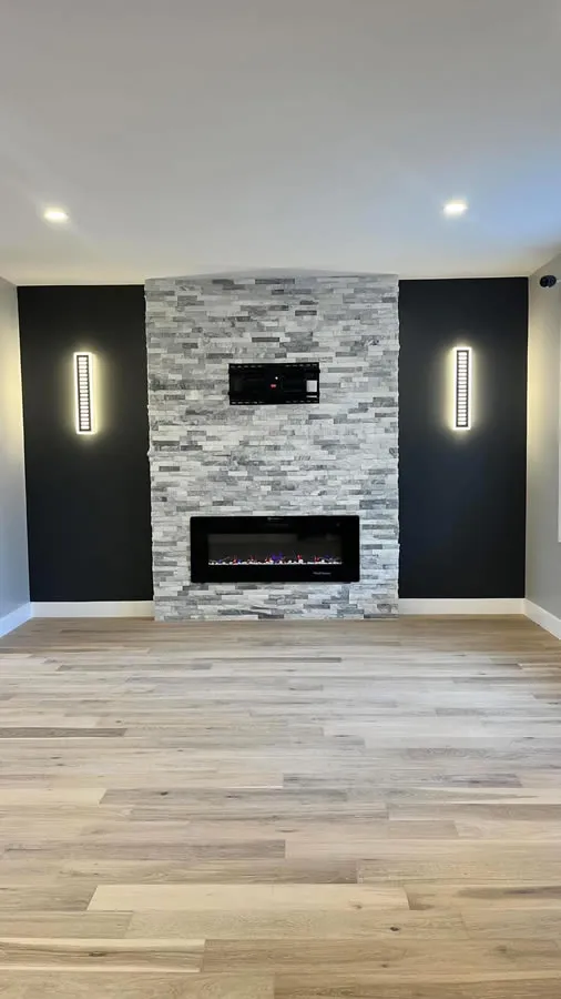 Rec room feature wall in stacked stone with a linear electric fireplace and recessed lighting